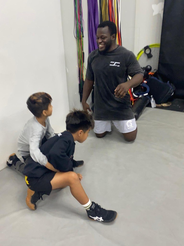 Coach Sauce training youth wrestlers on the mat